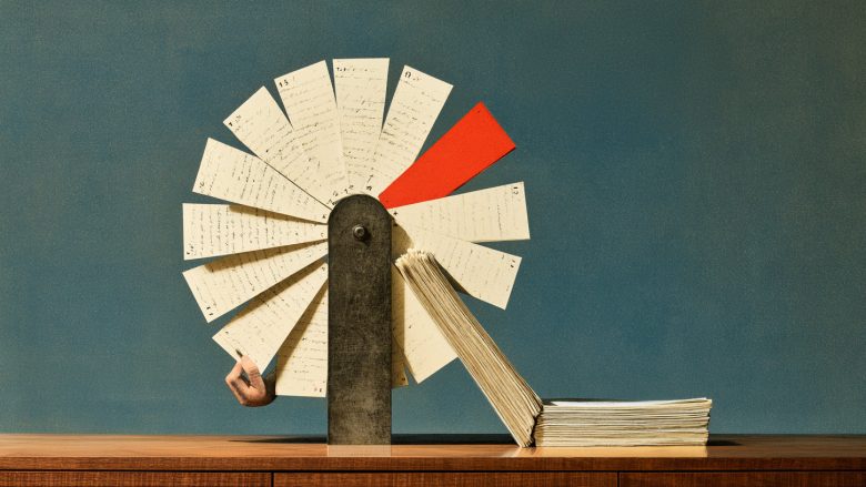 A vintage rotary card file with handwritten cards fanned out, one red card among cream-colored ones, a hand reaching to touch a card