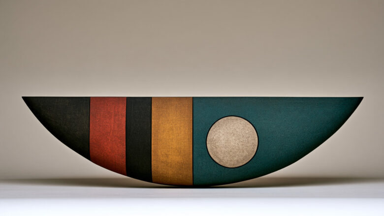Curved bowl-shaped sculpture with black, red, ochre and teal bands and a pale circle